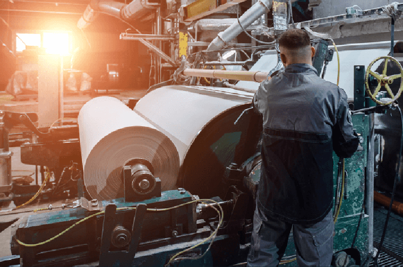 Paper mill in operation with a maintenance engineer checking the status.