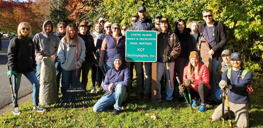 KCF Team at the Centre Region Parks & Recreation area photographed around the sign stating they are a Parks Partner. They are carrying equipment to clean and maintain the area.