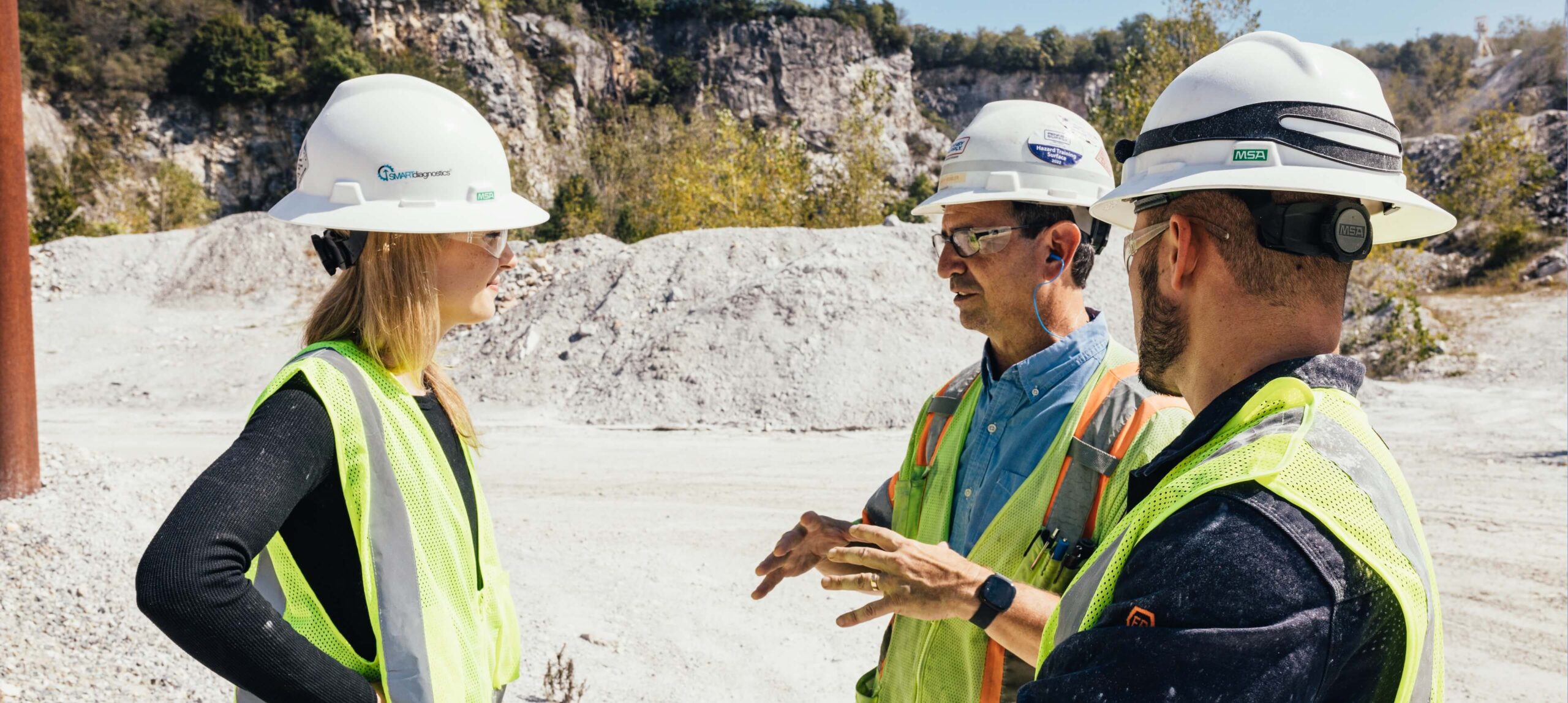 KCF team discusses solutions on site, wearing white hardhats and PPE.