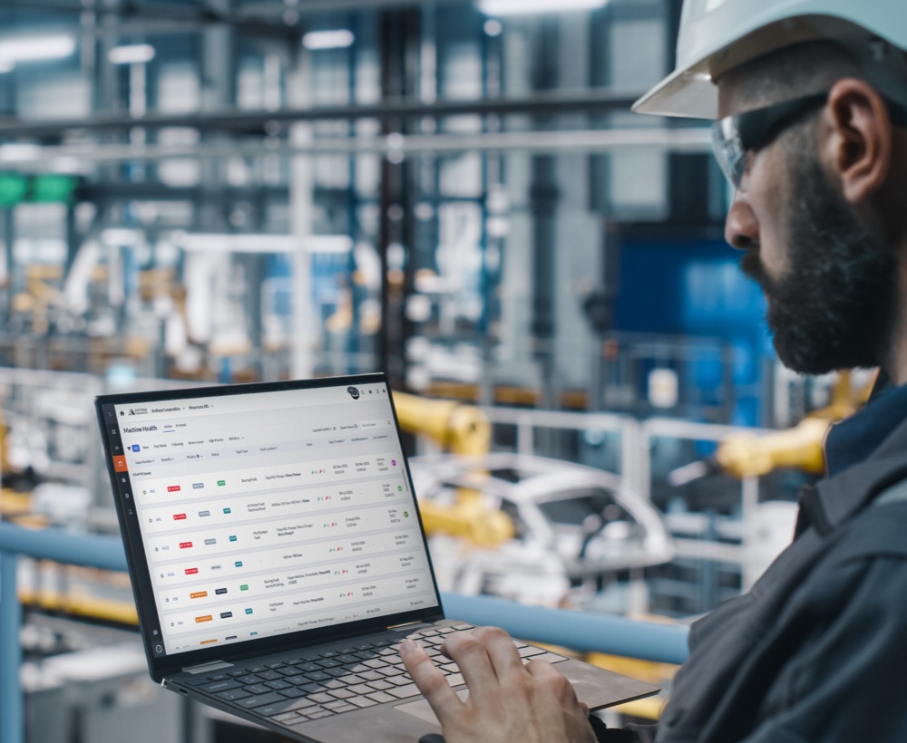 Plant maintenance engineer monitors machine health on their laptop.