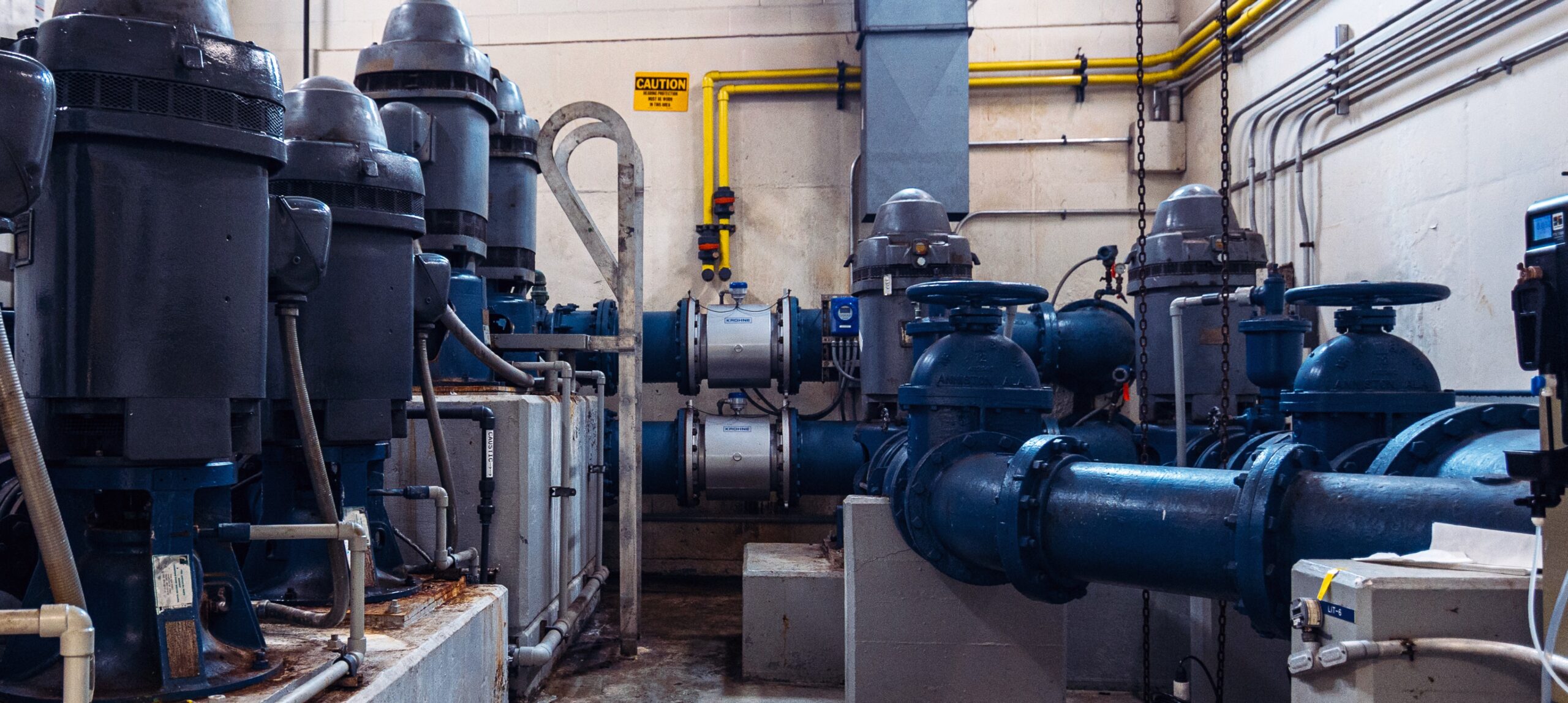 Wastewater plant shown with pumps and large scale blue plumbing.