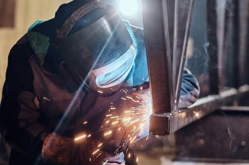 Welder works on truss in their plant.