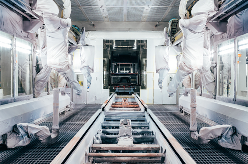 Automotive paint room showing equipment, spray arms, and track.