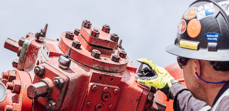 Engineer places vibration monitor on red industrial machinery to monitor machine health.