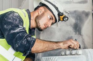 KCF employee places vibration monitor on industrial machinery to check bearings.