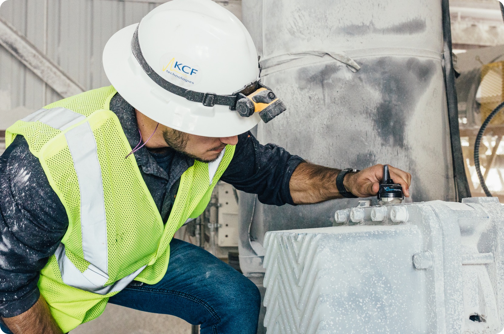 KCF Technologies employee places a SMARTdiagnostics wireless vibration sensor on industrial machinery to inform OEE analysis.