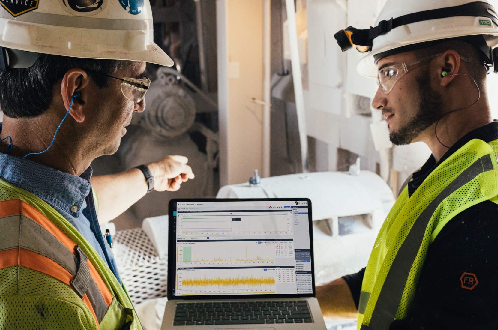 Two maintenance engineers discuss the data from predictive maintenance equipment, preventing downtime.
