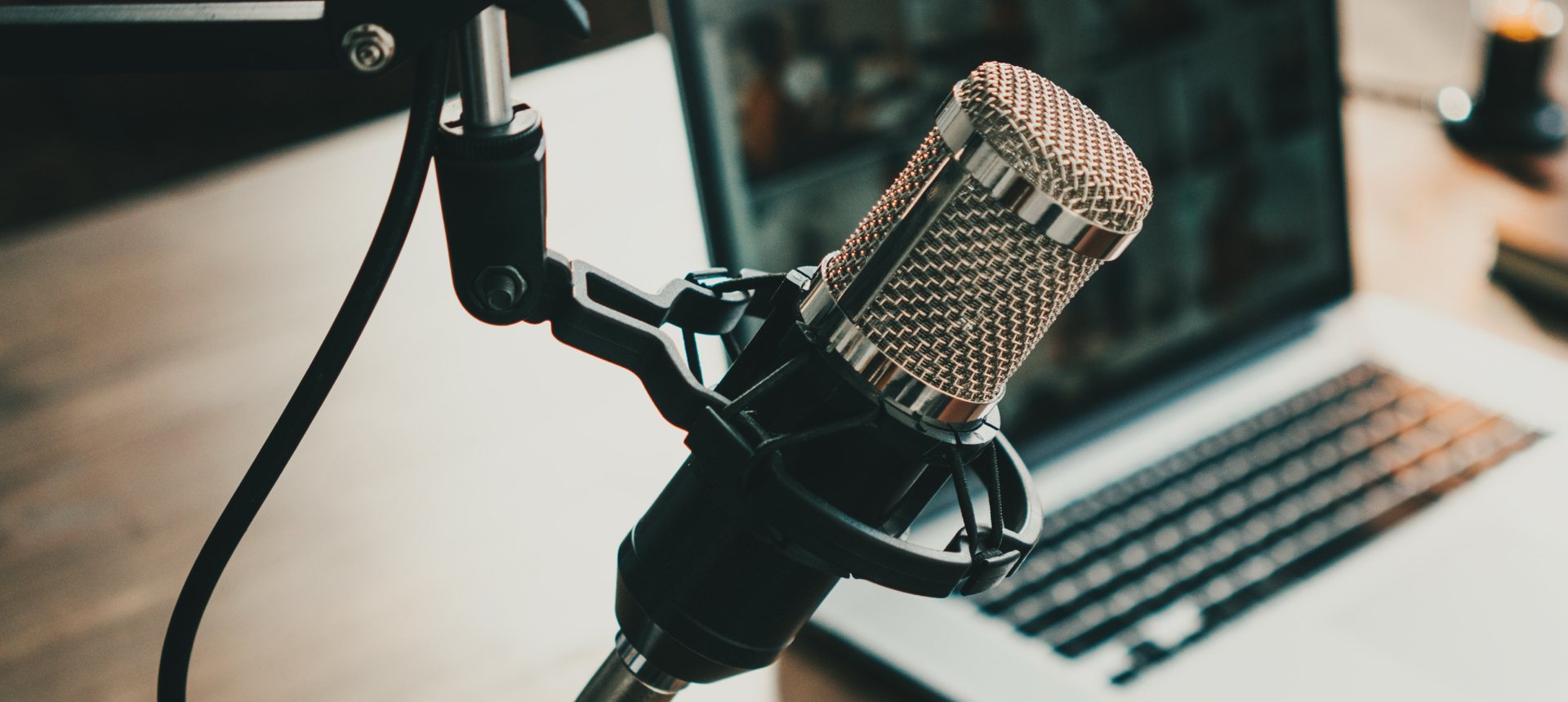 Podcast microphone in the foreground with a laptop in the background.