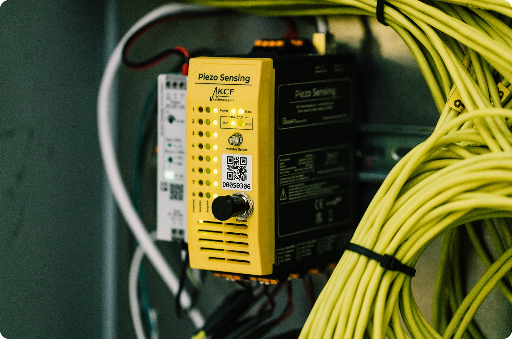 SMARTsensing Suite Piezo Sensor with a yellow face plate and black machine body connected to many yellow, black and red, and white wires.