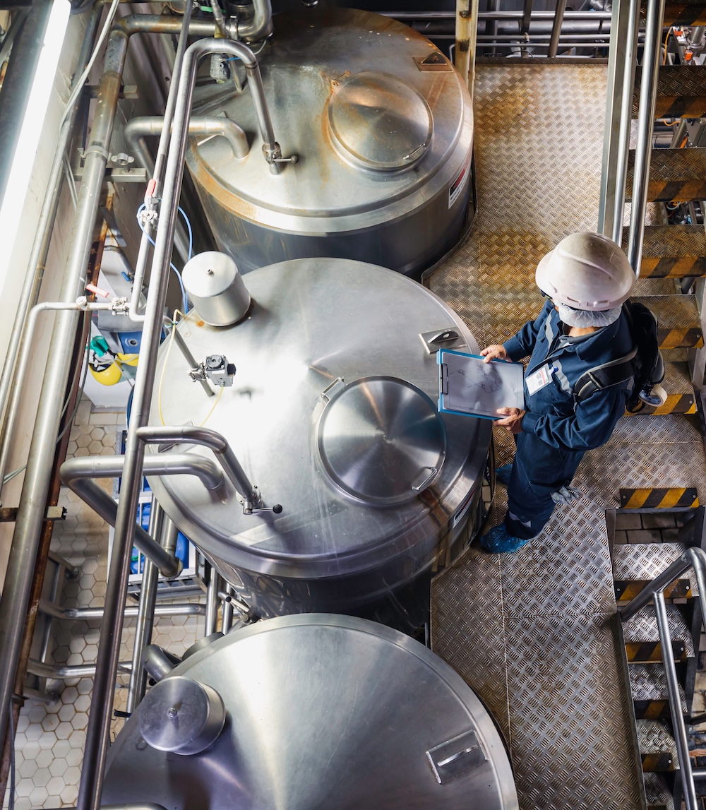 Worker inspecting large stainless tanks